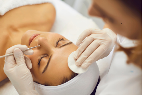 A skincare professional performing a facial treatment, using a comedone extractor to remove blackheads and impurities from the client's skin, helping improve skin clarity and texture.