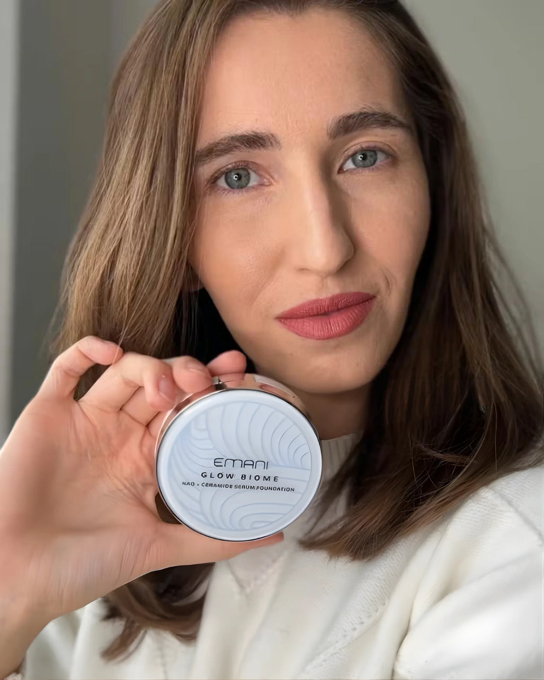 Woman holding a cosmetic product with 'EMANI' branding | Lena Levcenco
