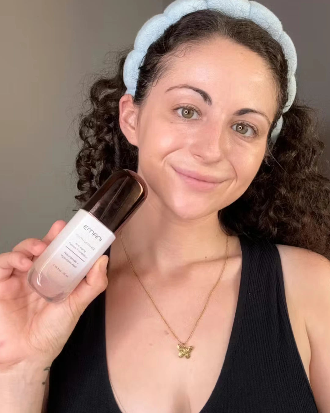 Woman holding a skincare product with a neutral background | Vanessa Maytlis