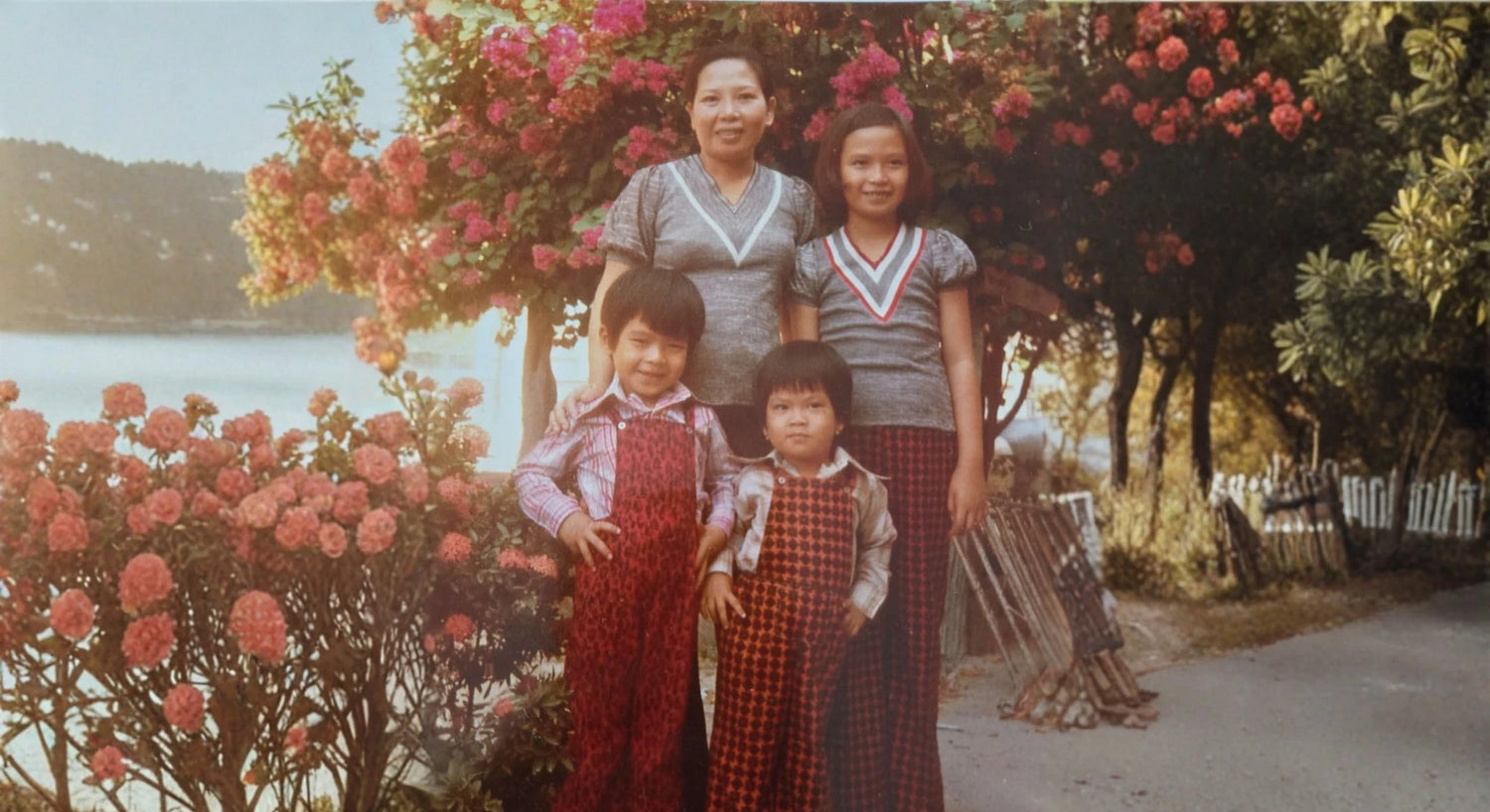 Family of four standing in front of a flowering tree by a body of water.